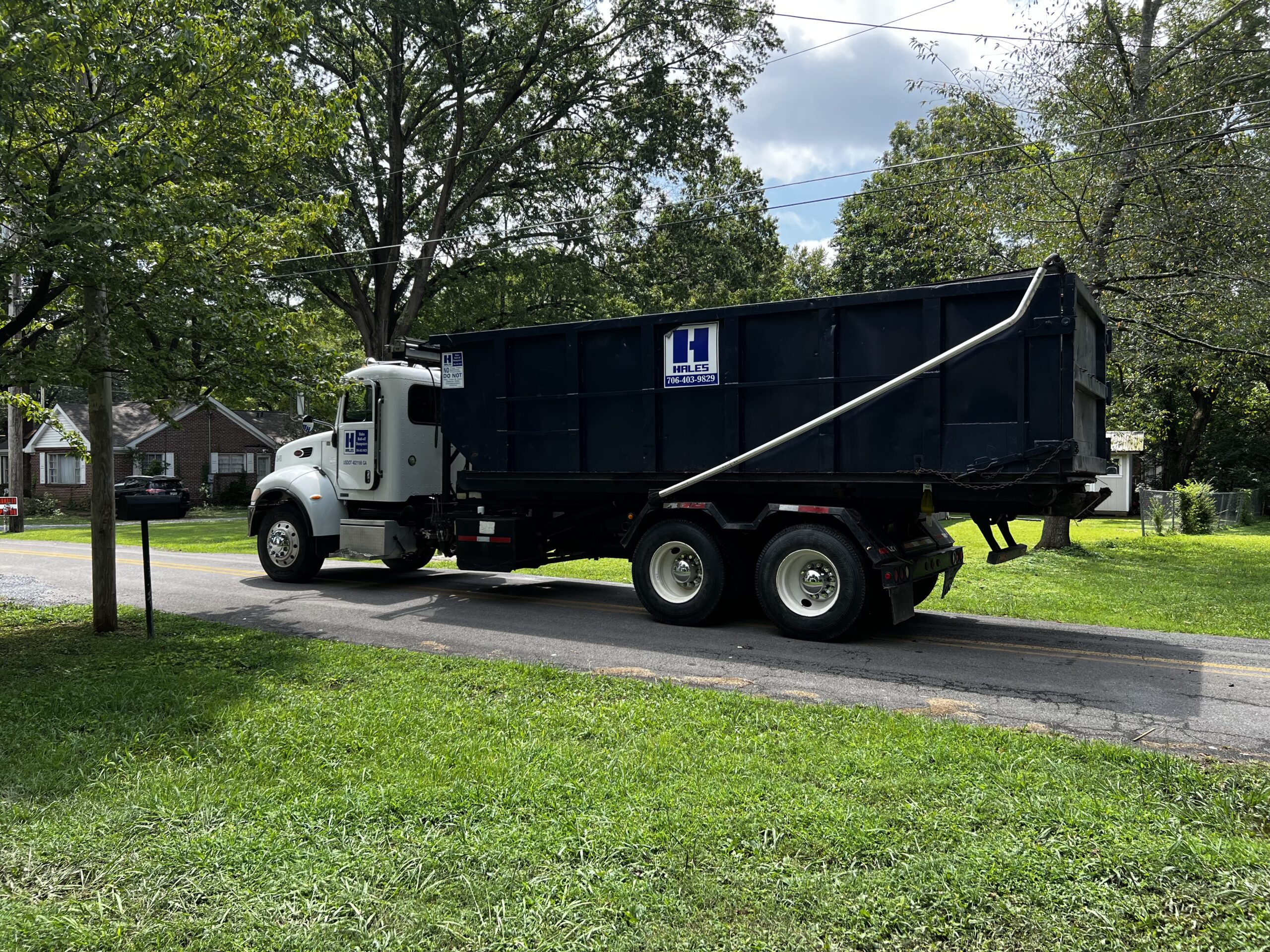 Roll-off dumpster and truck parked in a homeowner's yard. 