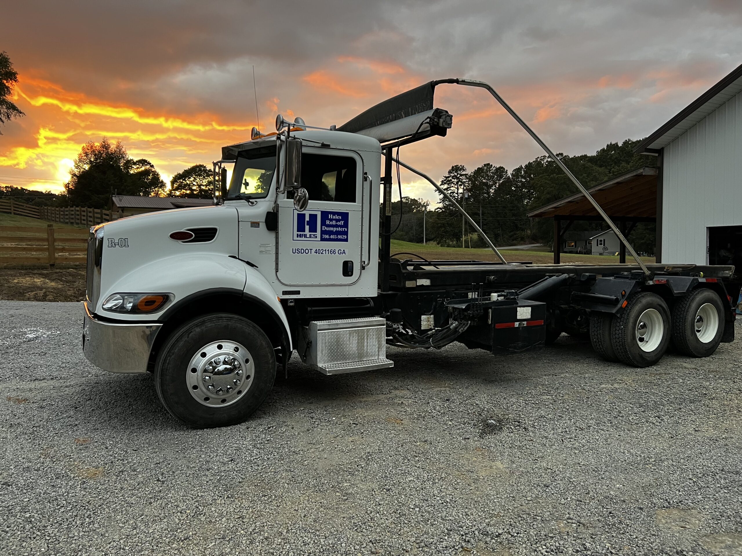 Hales Roll-off truck delivering a dumpster rental at sunset in Gordon County, GA.