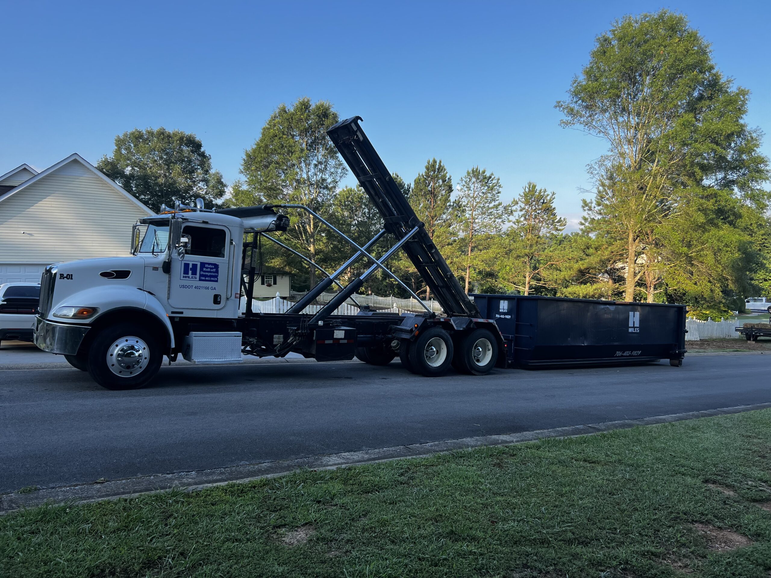Dumpster rentals in Northwest Georgia - Hales Roll-Off truck delivering a roll-off dumpster to a residential driveway.
