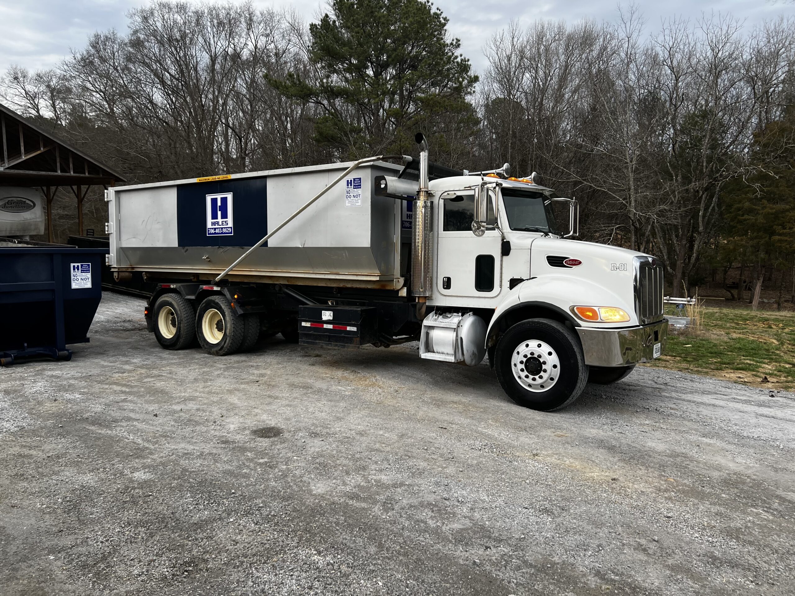 Silver roll-off truck used for dumpster rentals in Northwest Georgia, delivering containers to residential and commercial sites. 